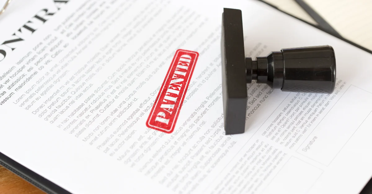 A contract laid out on the table that has been stamped by the words patented in red colour | KASS International